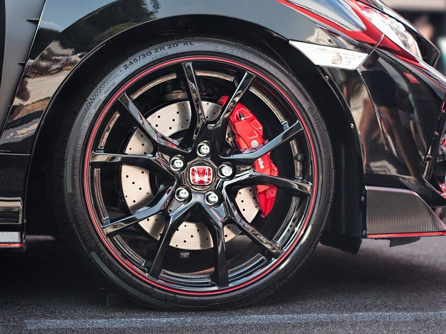 Red brake caliper and vented disc behind a black alloy wheel