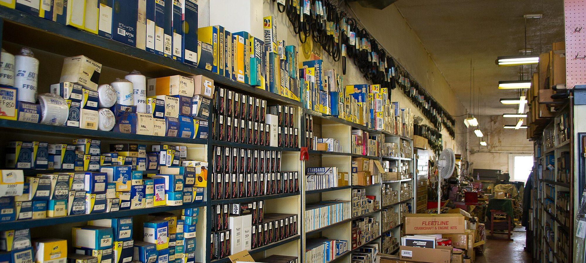 Aisle of an independent auto parts store, shelves stacked with boxed parts