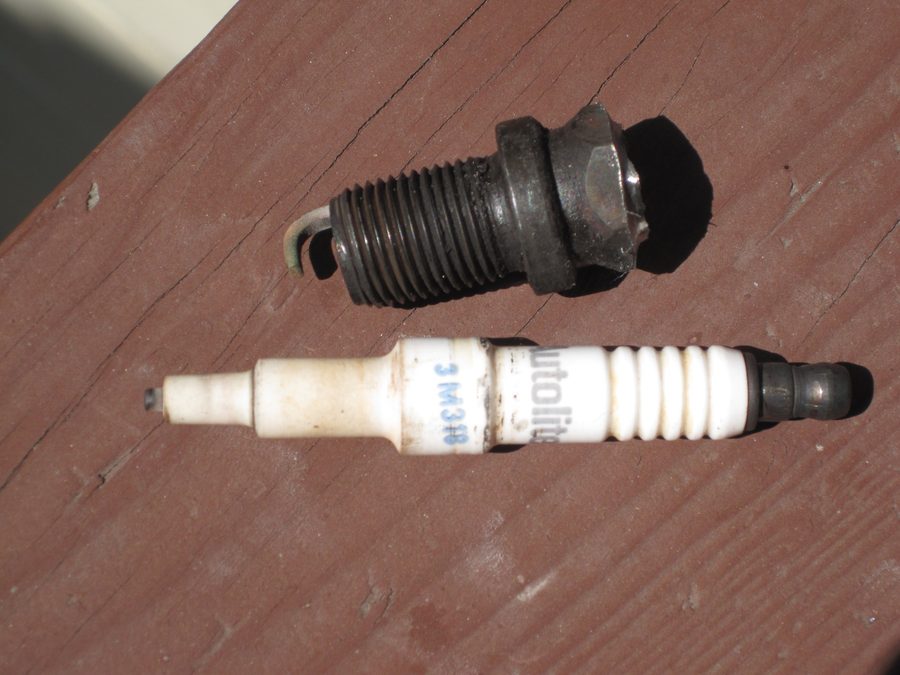 A worn spark plug beside a new one, showing electrode wear